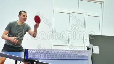 运动员乒乓球男子练习火车顶旋在右边。 男子在室内乒乓球运动